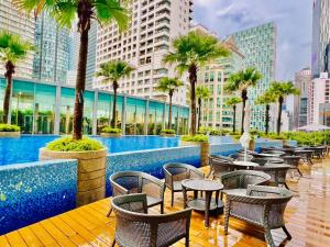 a hotel patio with tables and chairs and palm trees at Vortex suites KLCC By Moonlight in Kuala Lumpur