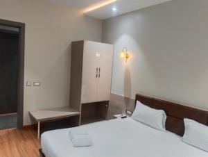 a bedroom with a white bed and a cabinet and a chair at Buddha Stays in Varanasi