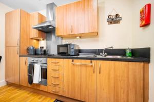 a small kitchen with wooden cabinets and a sink at Cozy 2 Bed Arcadian Center By Azura Nights in Birmingham