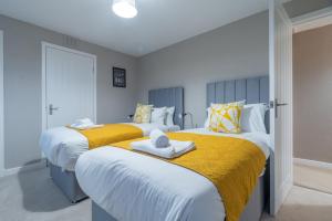 duas camas num quarto com lençóis amarelos e brancos em Kingswood em Bishopton