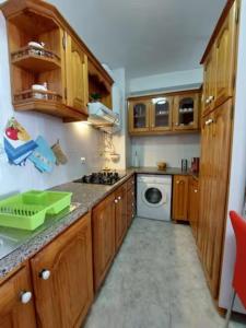 a kitchen with wooden cabinets and a washing machine at Barbara Home in Madalena do Mar +5 photos