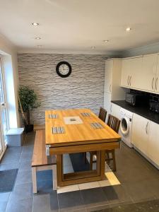 cocina con mesa de madera y reloj en la pared en Lovely family home, 5 minutes from the beach, en Clacton-on-Sea