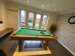 una mesa de billar en una habitación con reloj en Lovely family home, 5 minutes from the beach, en Clacton-on-Sea