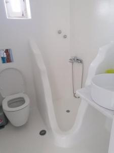 a white bathroom with a toilet and a sink at Mykonos Rooms in Agios Stefanos
