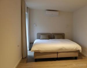 um quarto com uma cama num quarto branco em PRET A GOUTER bistro bar bed em Heusden - Zolder