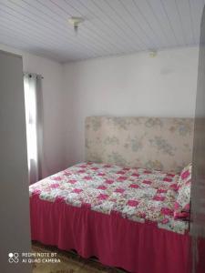 Schlafzimmer mit einem Bett mit einer roten Bettdecke in der Unterkunft Casa no centro da cidade a 600 metros da praia. in Porto Belo