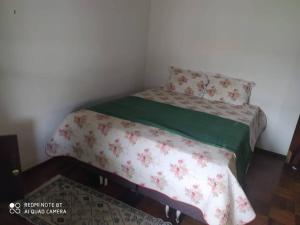 ein kleines Schlafzimmer mit einem Einzelbett mit einer grünen Decke in der Unterkunft Casa no centro da cidade a 600 metros da praia. in Porto Belo