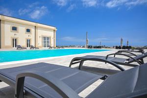 grupa krzeseł siedzących obok basenu w obiekcie Dimora Savarino Marzamemi Suites with pool w mieście Marzamemi