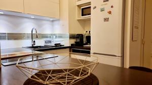 cocina con mesa de cristal y nevera en Appartement deluxe ac 1 chambre proche Paris Disney 20min rerA ou A4, en Noisy-le-Grand