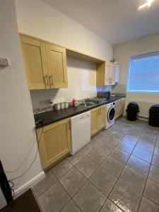 a kitchen with yellow cabinets and a white dishwasher at Huge 6 Bed house & 6 Bathrooms. in Boston