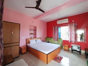a bedroom with a bed and a red wall at Muktomon Hotel & Resort in Bolpur