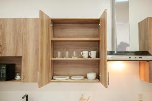 a kitchen with wooden cabinets with dishes and a microwave at Casa Valencia 1 in Santa Elena