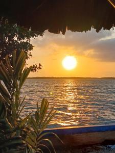 um pôr-do-sol sobre um corpo de água em Cabaña de playa San José Coveñas em El Porvenir