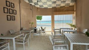 a restaurant with tables and chairs and a view of the ocean at Alimas Holiday Retreat Maldives in Felidhoo