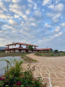 ein Gebäude auf einem Feld mit wolkigem Himmel in der Unterkunft Hotel Palais Barichara in Barichara