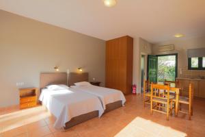 a bedroom with a bed and a table and a kitchen at Vivi's Apartments in Ayia Evfimia