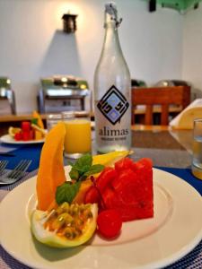 une assiette de fruits sur une table avec une bouteille dans l'établissement Alimas Holiday Retreat Maldives, à Felidhoo