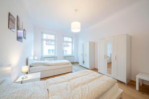a white bedroom with two beds and a cabinet at Apt Volt - Modern, neu, komplett ausgestattet, 4 Einzelbetten, zentral mit Waschmaschine Spülmaschine TV Herd Backofen Mikrowelle in Fürstenwalde +6 photos