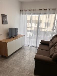 uma sala de estar com uma televisão e um sofá em Apartamento en Los cristianos 2 habitaciones 4 huespedes Vv Elenita em Los Cristianos