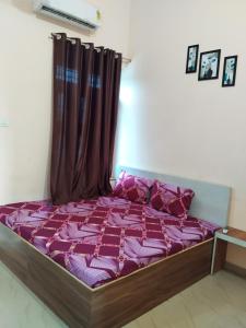 a bed with a purple comforter and a curtain at Shiv Shakti Palace in Rīngas +3 photos