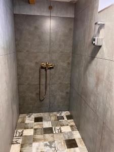a bathroom with a shower with a tiled floor at Hnameni Bovadzor Lodge in Maksim Gorʼkiy