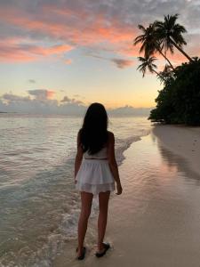 a little girl standing on the beach watching the sunset at Alimas Holiday Retreat Maldives in Felidhoo