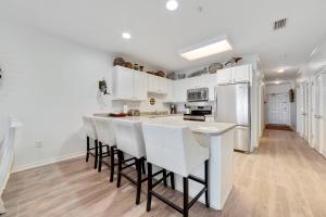a kitchen with white cabinets and a bar with stools at Marlin Key 3C in Orange Beach