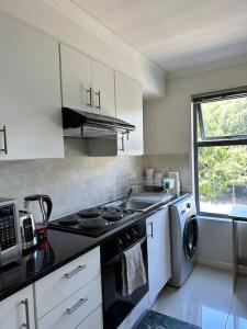 a kitchen with a stove and a sink and a microwave at Cozy Rondebosch Apartment in Cape Town