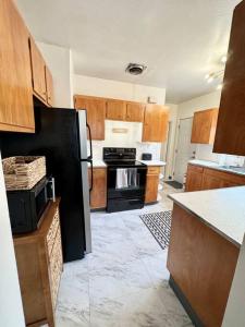 eine Küche mit Holzschränken und einem schwarzen Kühlschrank in der Unterkunft Tandem House - 3 Bedroom SE Portland Gem! in Portland