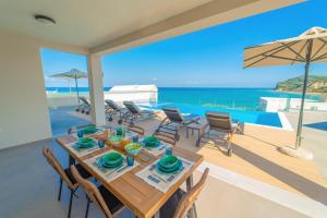 una sala da pranzo con tavolo, sedie e vista sull'oceano di Villa Halcyon ad Agios Stefanos