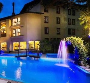 a swimming pool with a fountain in front of a building at Suite Confort - Gramado Wish Serrano in Gramado