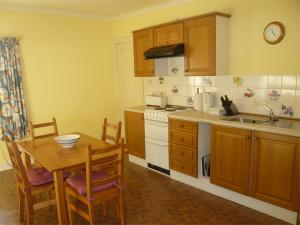 a kitchen with wooden cabinets and a table and a sink at 2 Bed in Kinlocheil CA138 in Fassfern
