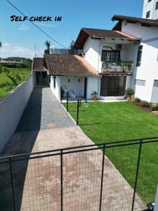 uma casa com uma cerca em frente a um quintal em RCM Vilas - Casa Confortável 02 em Joinville