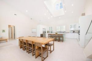 a large white kitchen with a wooden table and chairs at Ocean Kai home in Driftwood Village