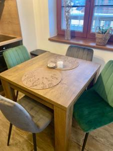 a wooden table with green chairs and a wooden table at Apartmán v Kašperských Horách in Kašperské Hory