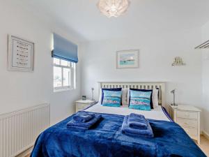 3 Bed in Appledore 28479 في آبيلدوور: غرفة نوم مع سرير ذو أغطية زرقاء ومخدات زرقاء