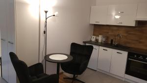 a kitchen with two chairs and a table and a lamp at Komfortowy apartament w centrum Nowego Sącza in Nowy Sącz