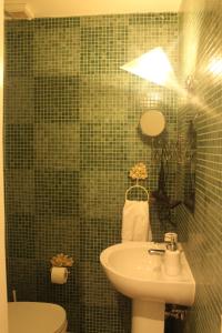 a green tiled bathroom with a sink and a toilet at La Casetta 2 -10 min Aeroporto e spiaggia in Fiumicino