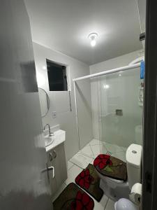 La salle de bains est pourvue d'une douche et de toilettes avec des roses rouges au sol. dans l'établissement Hotel Mirante, à Barra Velha