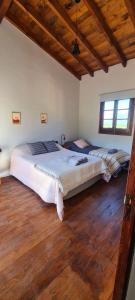 two beds in a bedroom with wooden floors at Las Piedritas Cafayate in Cafayate