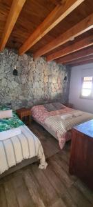 a bedroom with two beds and a stone wall at Las Piedritas Cafayate in Cafayate