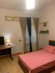 een slaapkamer met een bed en een bureau met een televisie bij Luxury Apartment Nasr City in Caïro