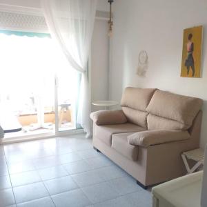 uma sala de estar com um sofá e uma grande janela em Apartamento ALOHA BABY a 2 calles del Mar em Sant Salvador