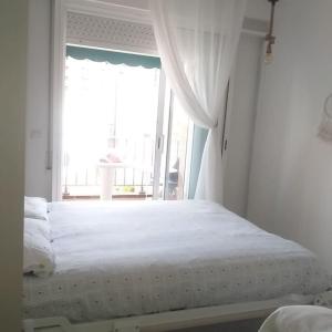 um quarto com uma grande cama branca e uma janela em Apartamento ALOHA BABY a 2 calles del Mar em Sant Salvador