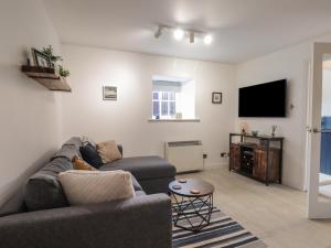 sala de estar con sofá y TV de pantalla plana en Flat 4, The Byre en Cromarty