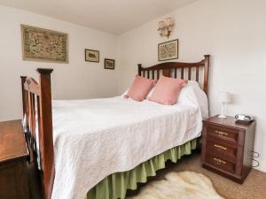 um quarto com uma cama com almofadas cor-de-rosa em Boothsteads Farm Cottage em Halifax