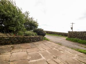 um caminho de pedra ao lado de uma parede de pedra em Boothsteads Farm Cottage em Halifax