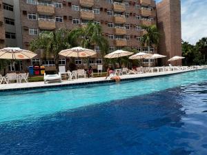 a pool with chairs and umbrellas in a hotel at Gran Lençóis Flat Barreirinhas APT 510 in Barreirinhas