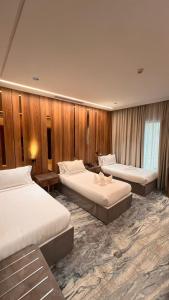 una camera d'albergo con tre letti e pareti in legno di فندق ماسة المشاعر الفندقية a La Mecca