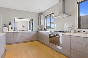 a kitchen with white cabinets and stainless steel appliances at Luxury Lake Hood Holiday Home in Wakanui